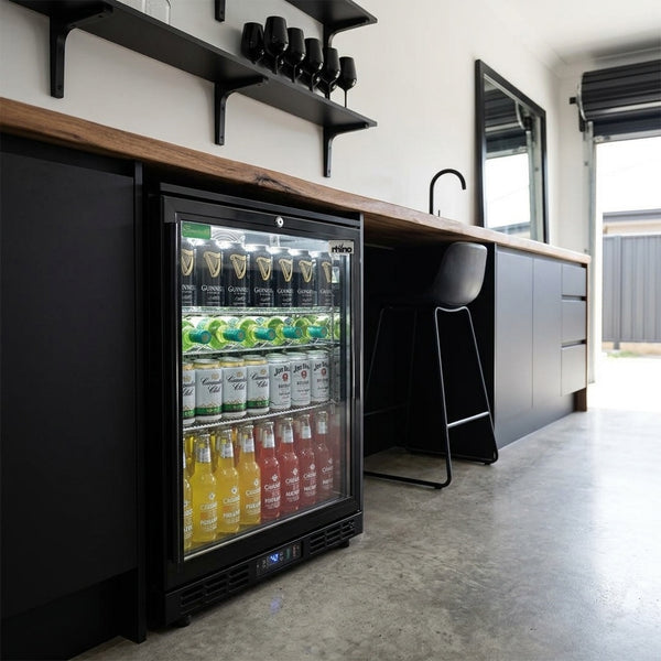 Rhino SG1 Black HD bar fridge under a timber benchtop in a premium garage bar with polished concrete floor