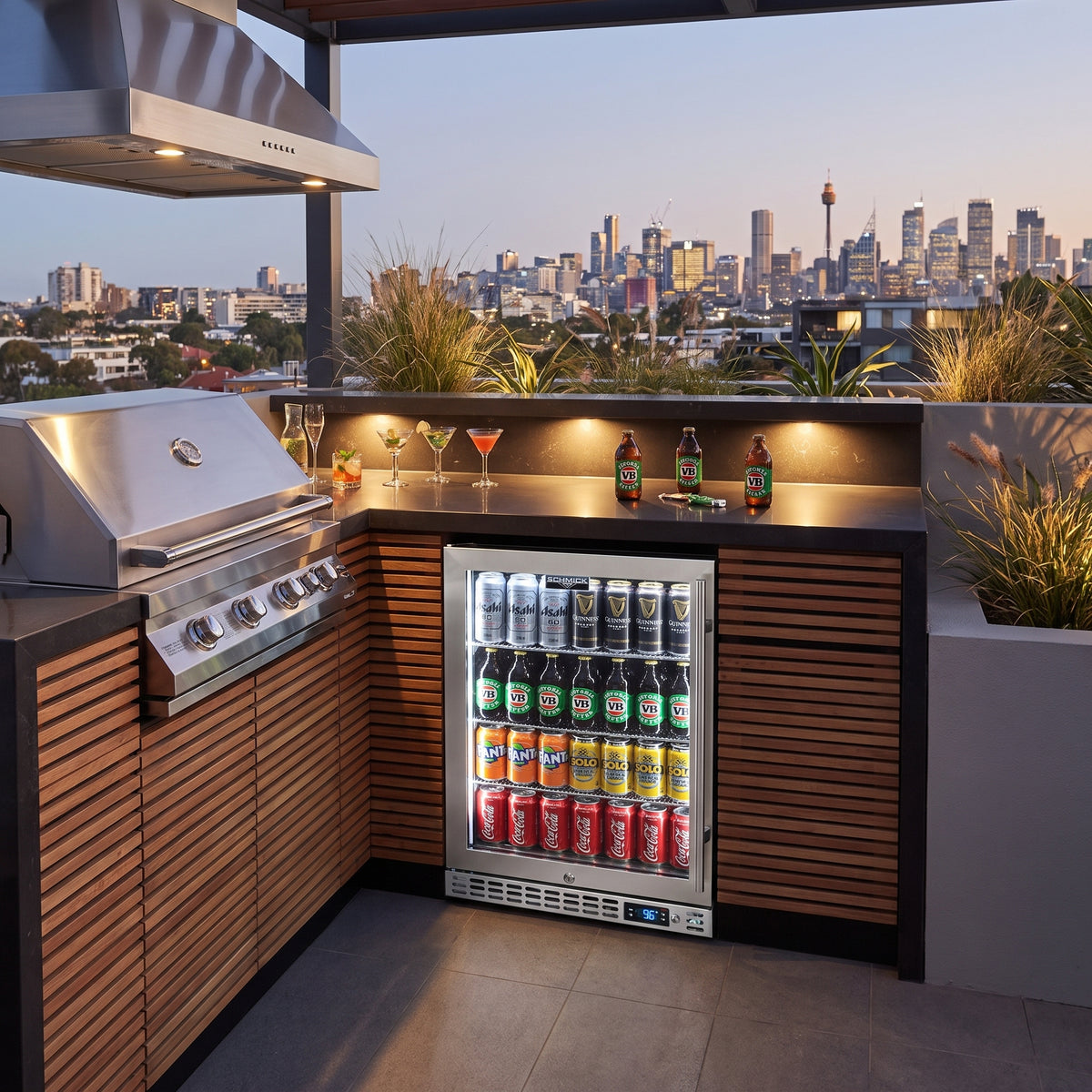 Schmick SK126L-HD bar fridge built into an outdoor kitchen: rooftop terrace kitchen at twilight, stainless bbq and rangehood
