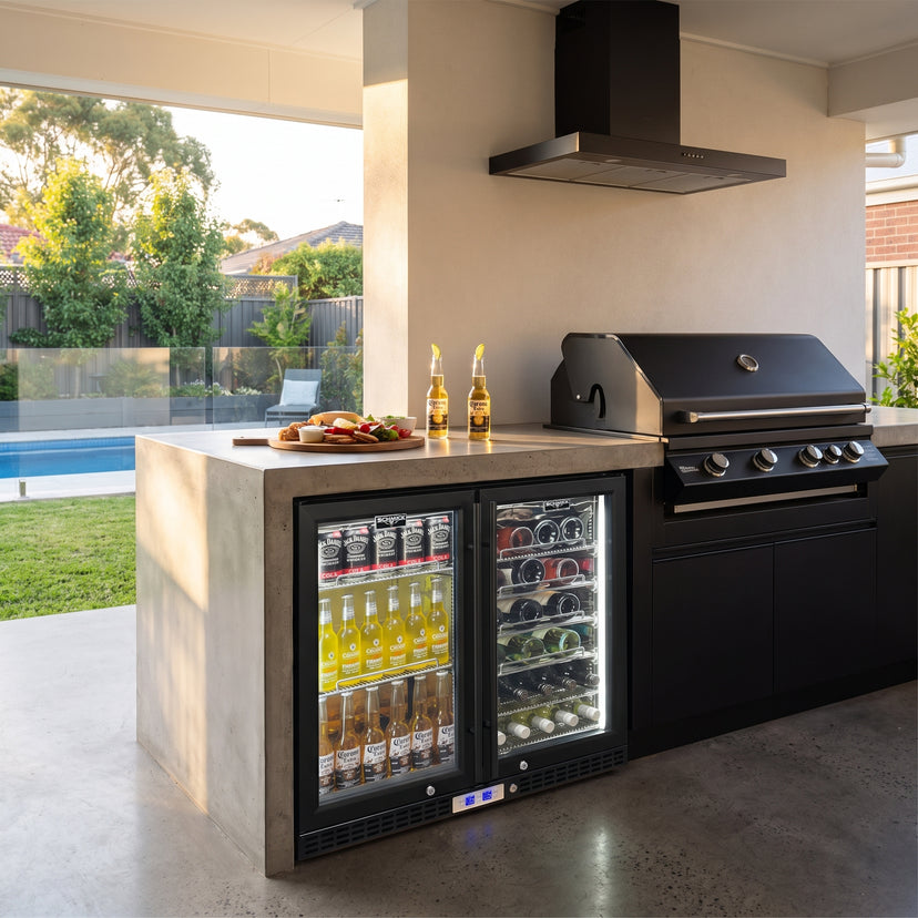 Schmick SK248D-B-HD dual zone bar fridge built into a concrete outdoor kitchen beside a black built-in BBQ and black rangehood